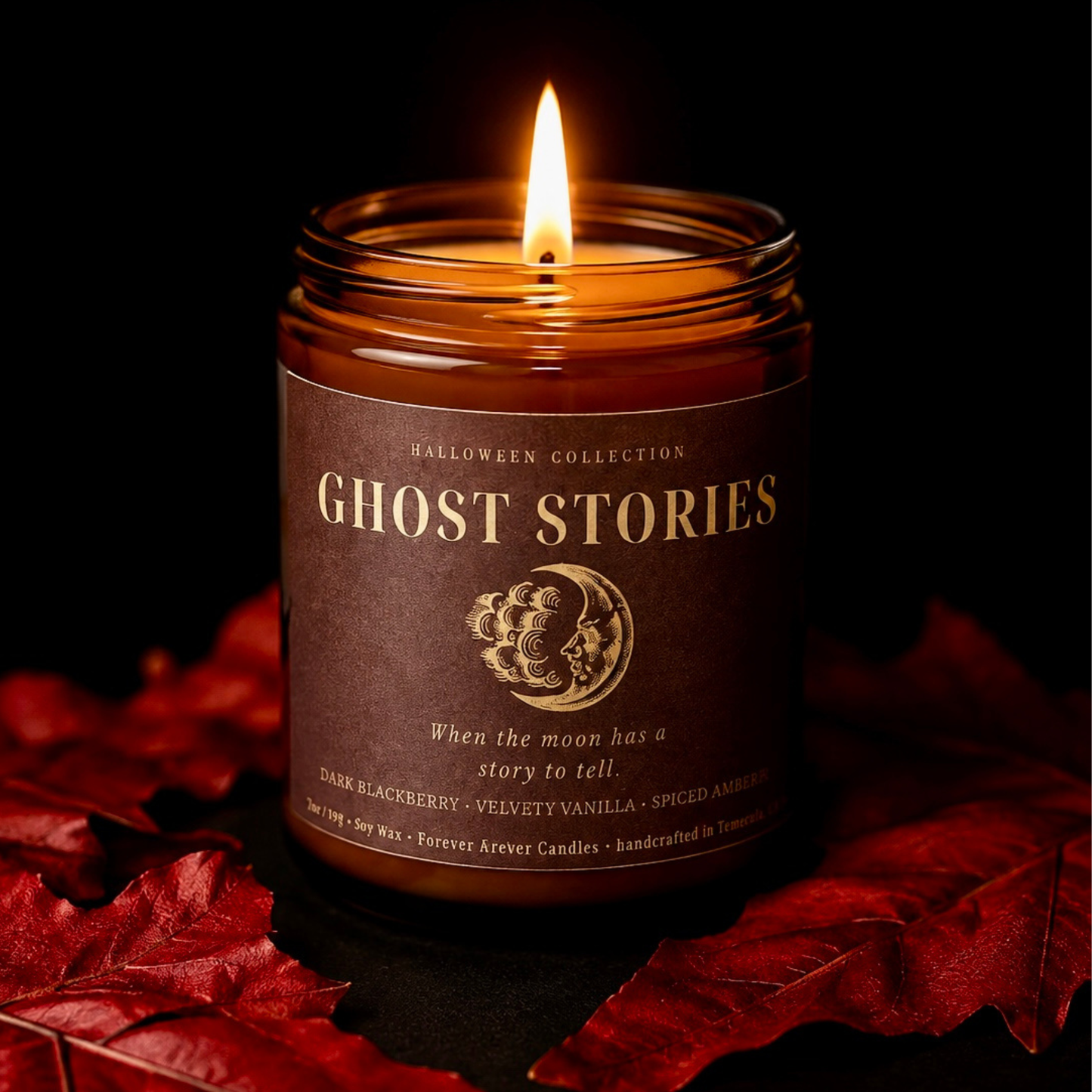 Lit Ghost Stories 7 oz soy candle from the Forever Amber Candles Halloween Collection surrounded by red autumn leaves