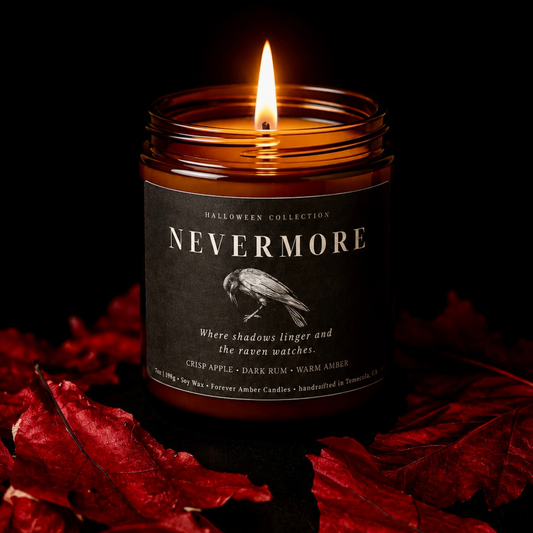 Lit Nevermore 7 oz soy candle from the Forever Amber Candles Halloween Collection surrounded by red autumn leaves
