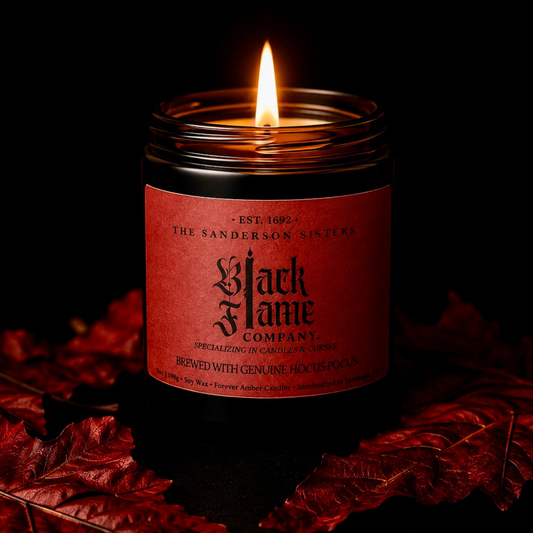 Lit Black Flame 7 oz soy candle from the Forever Amber Candles Halloween Collection surrounded by red autumn leaves
