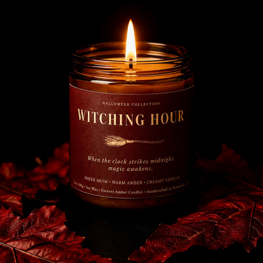 Lit Witching Hour 7 oz soy candle from the Forever Amber Candles Halloween Collection surrounded by red autumn leaves
